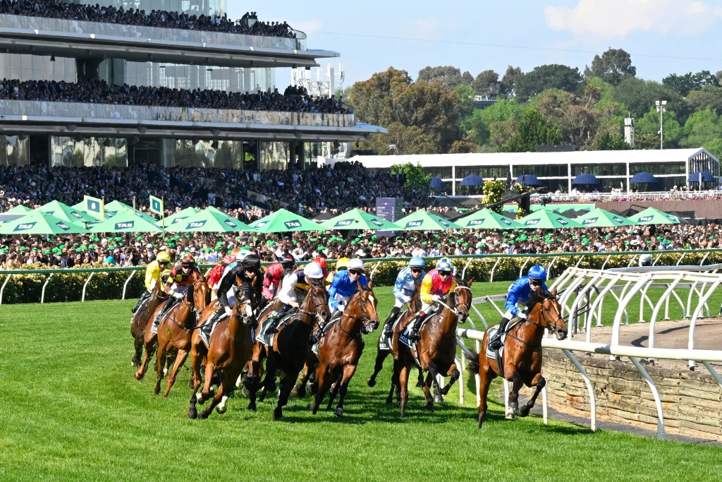 Field of horses and jockeys passing the 1400m marker during a TAB Vic Spring Carnival race